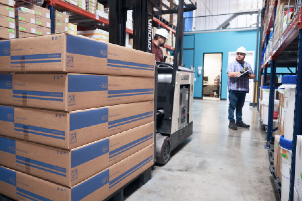 A photo of workers in a warehouse setting with a forklift truck and boxes