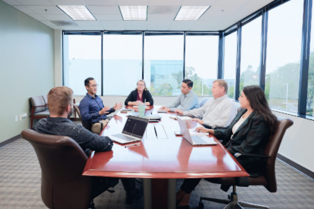 An image of a team sitting around a large table at Tanvex's headquarters in San Diego